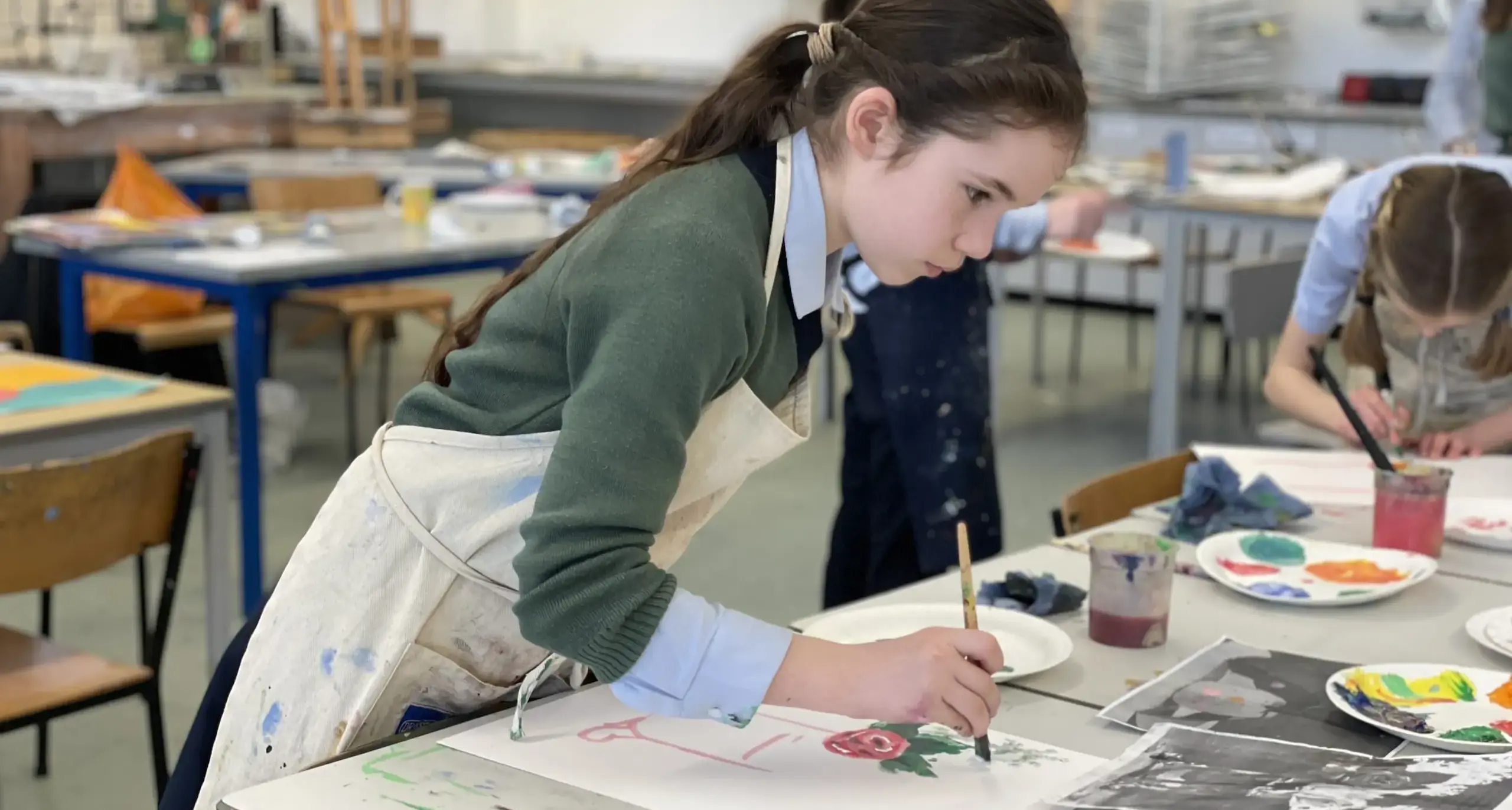 A young girl painting a flower in a classroom