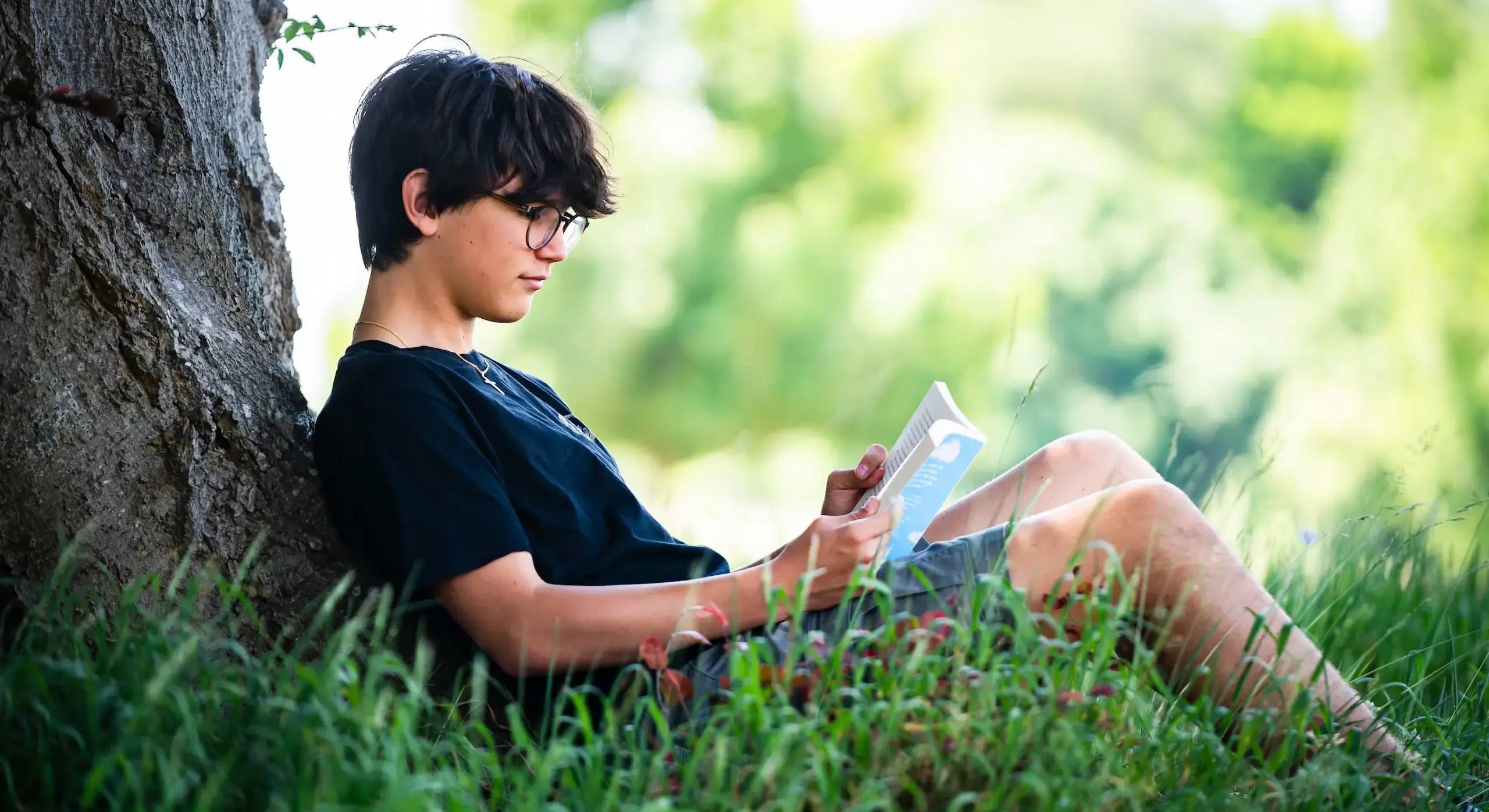 Embley pupil reading by a tree