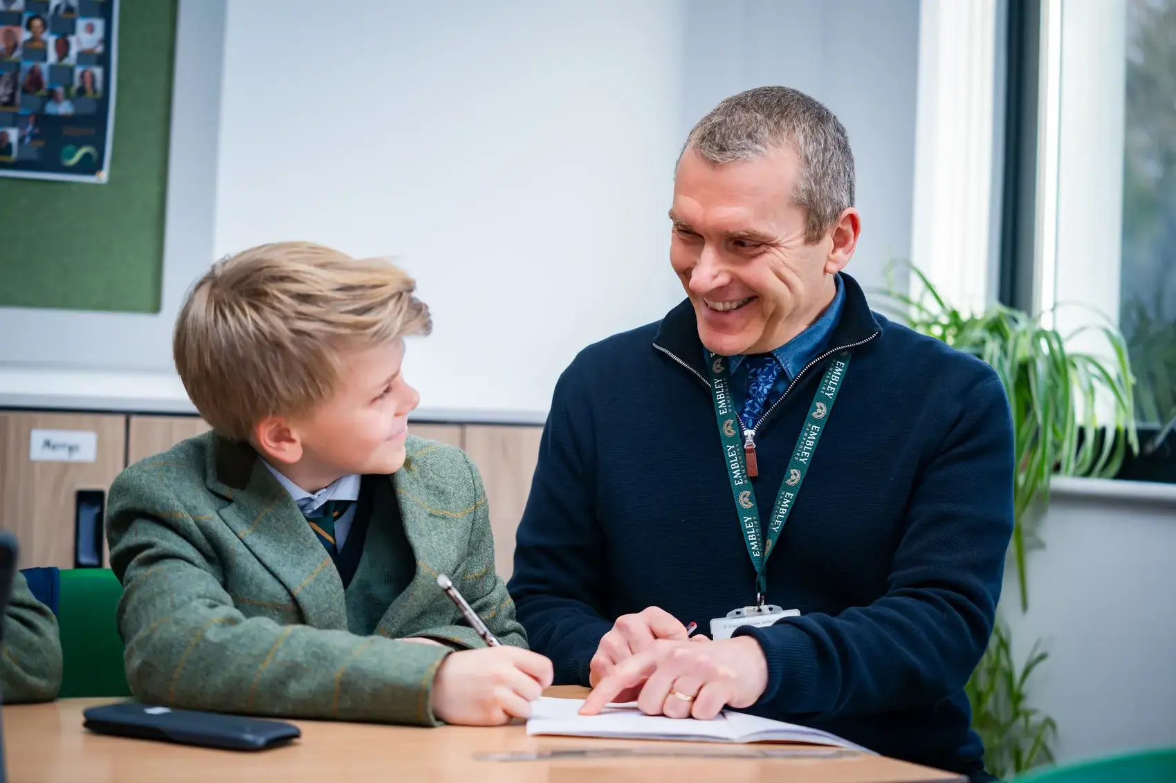 A teacher sitting with a pupil helping with his workon page image