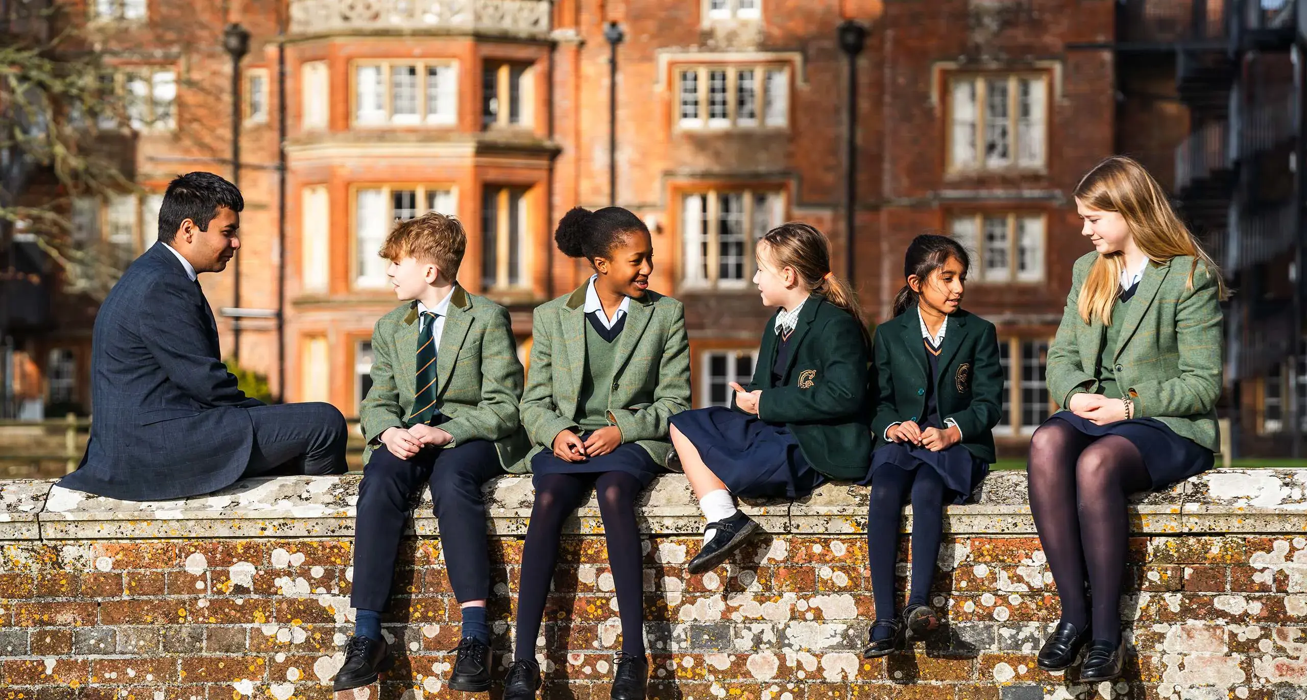 Embley students sitting on a ledge on campus.