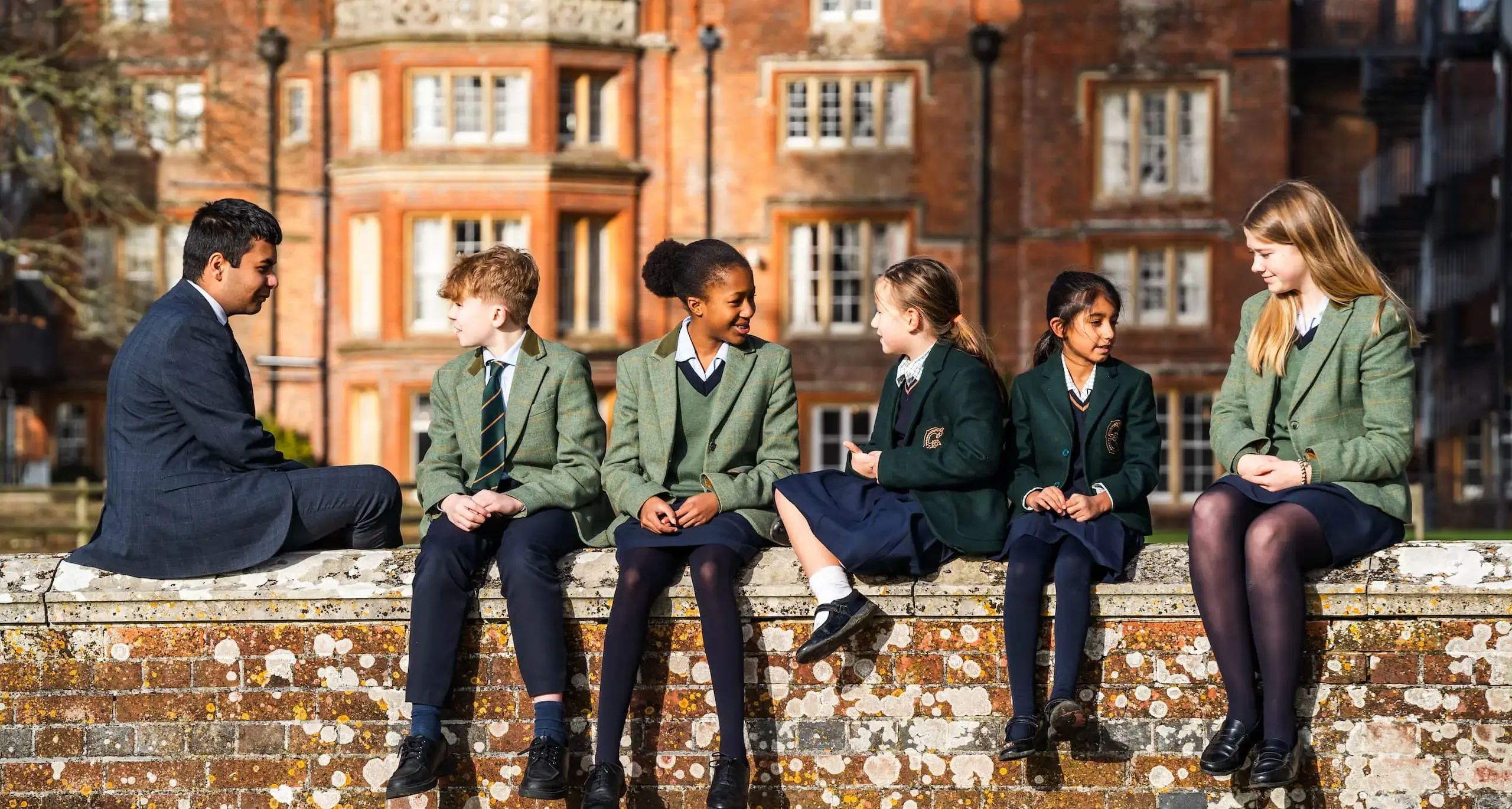 A group of students sitting on a wall chatting