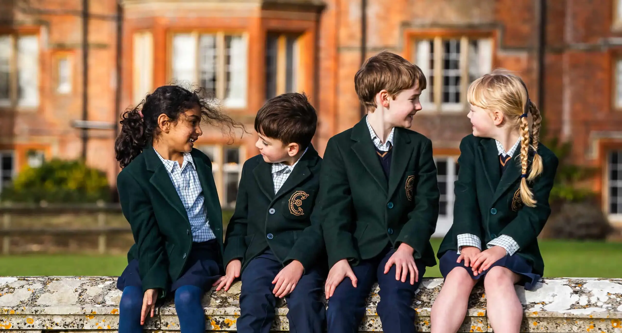 Group of Embley Prep students sitting on wall outside school building