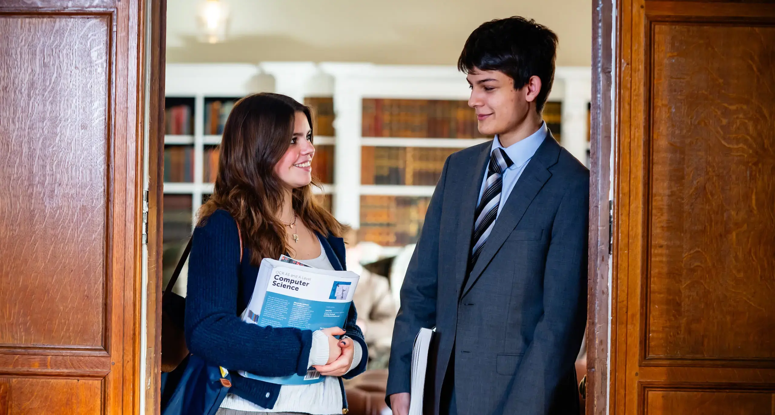 Two students standing in an office doorway.