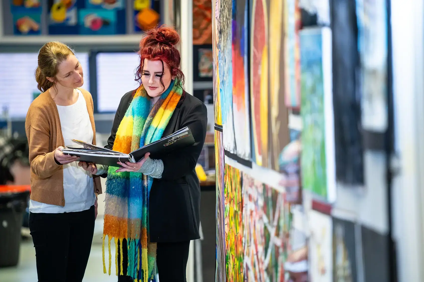 Student and teacher speaking near artwork.