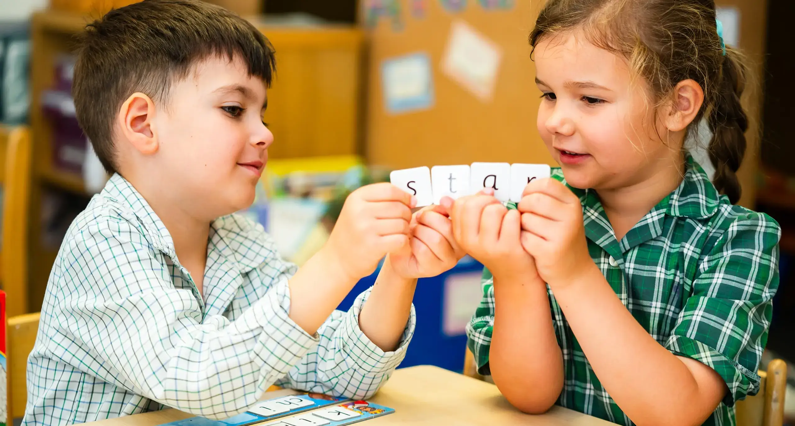 Young pupils spelling out the word 'star' with letter tiles