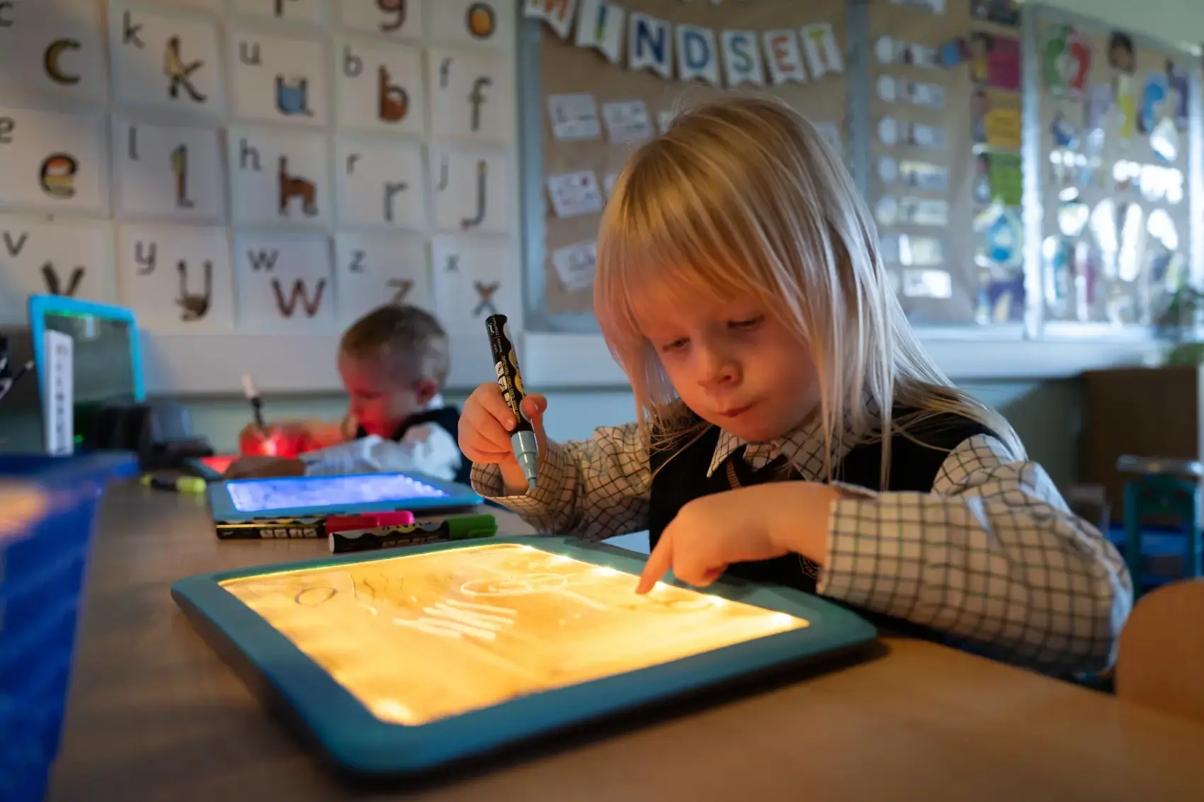 A young girl is using an iPad to draw