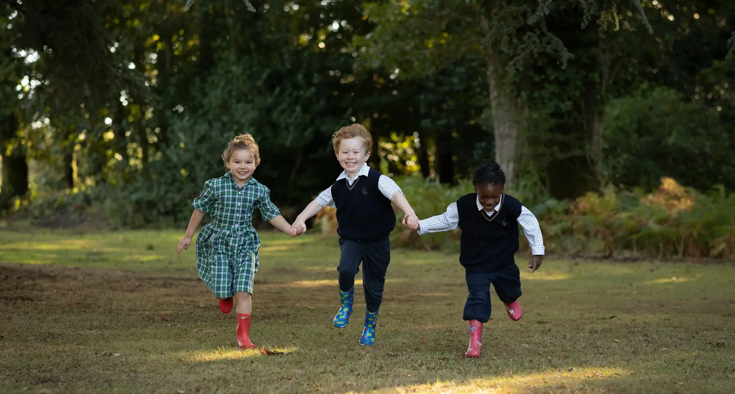 Three young students running outdoors.